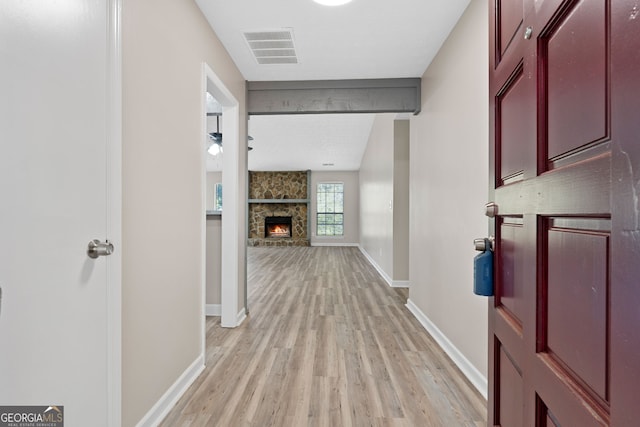 corridor featuring beamed ceiling, baseboards, visible vents, and light wood-style floors