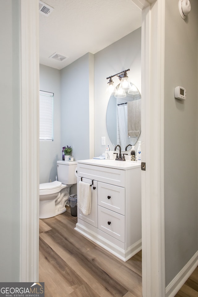 bathroom featuring wood-type flooring, vanity, and toilet