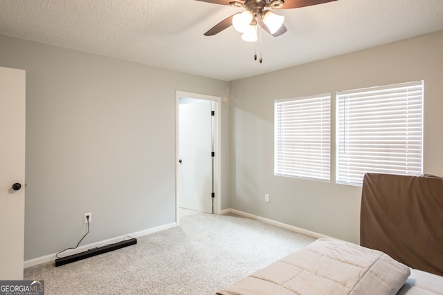 carpeted bedroom featuring ceiling fan and a textured ceiling