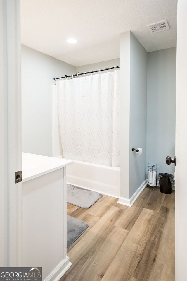 bathroom featuring vanity, shower / bath combination with curtain, hardwood / wood-style flooring, and a textured ceiling