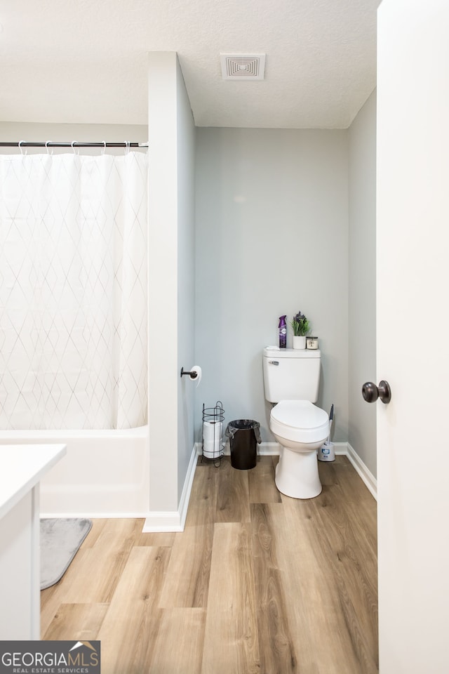 full bathroom with shower / bath combination with curtain, hardwood / wood-style floors, vanity, and toilet