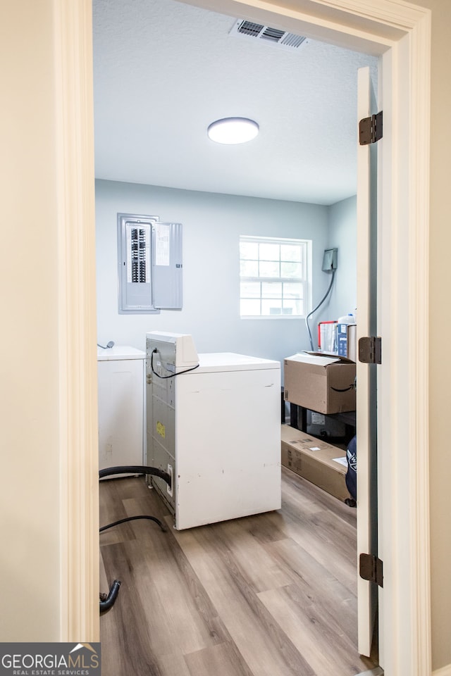 washroom featuring independent washer and dryer, electric panel, and light wood-type flooring