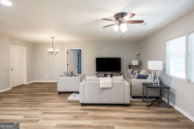 living room with ceiling fan with notable chandelier and hardwood / wood-style floors