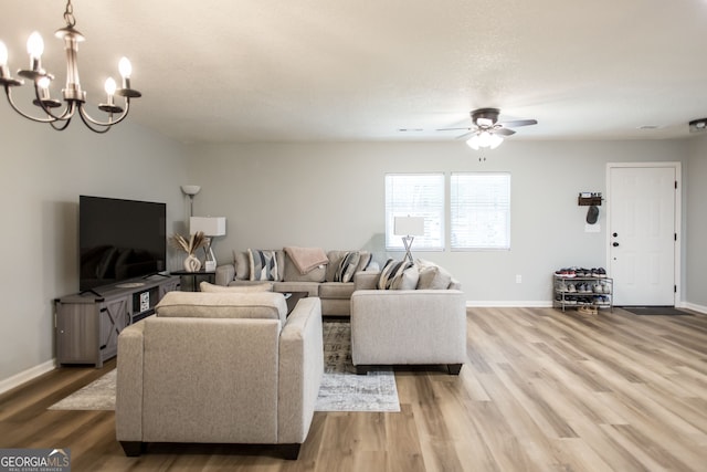 living room featuring ceiling fan with notable chandelier, hardwood / wood-style flooring, and a textured ceiling