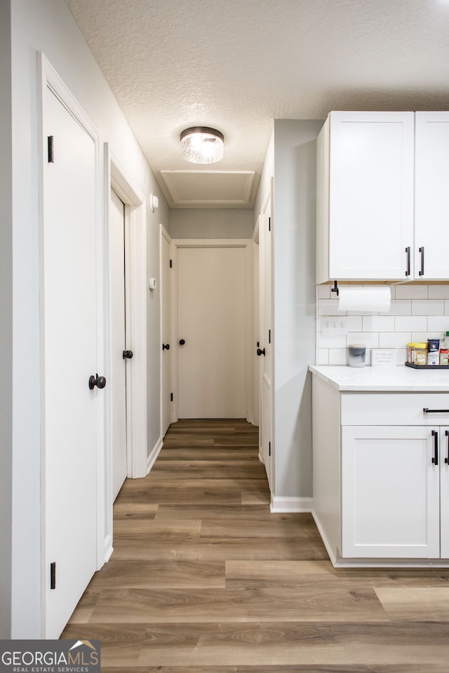 hallway with a textured ceiling and light wood-type flooring