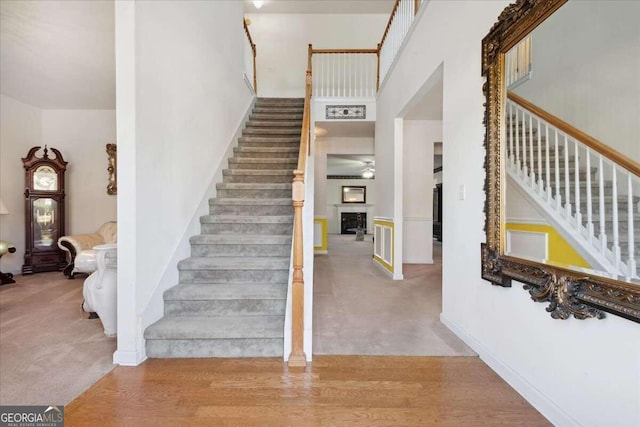 staircase with a towering ceiling and carpet flooring