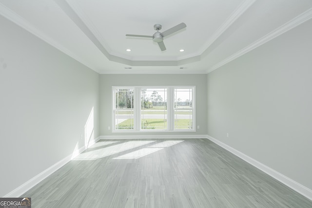 unfurnished room with ceiling fan, light wood-type flooring, ornamental molding, and a tray ceiling