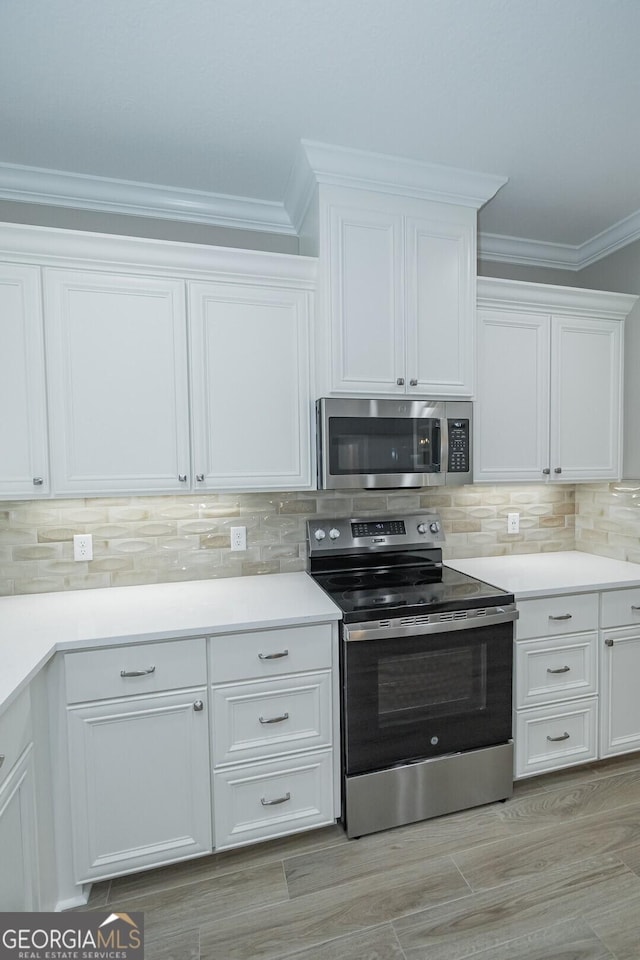 245 Ryan Nicholas Dr, Kingsland, GA 31548 - kitchen with decorative backsplash, appliances with stainless steel finishes, light countertops, ornamental molding, and white cabinetry