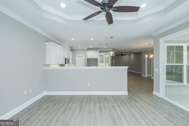 245 Ryan Nicholas Dr, Kingsland, GA 31548 - unfurnished living room with crown molding, a raised ceiling, and ceiling fan with notable chandelier