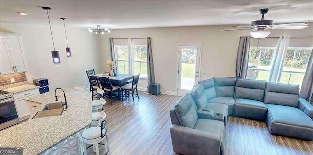 living room with ceiling fan with notable chandelier, sink, and hardwood / wood-style flooring