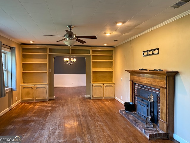 unfurnished living room featuring dark hardwood / wood-style floors, ceiling fan with notable chandelier, crown molding, a fireplace, and built in shelves