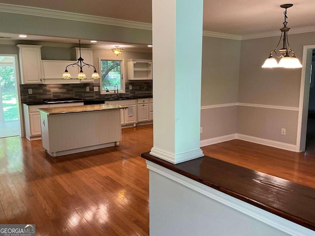 kitchen with decorative light fixtures, hardwood / wood-style flooring, a kitchen island, and white cabinetry