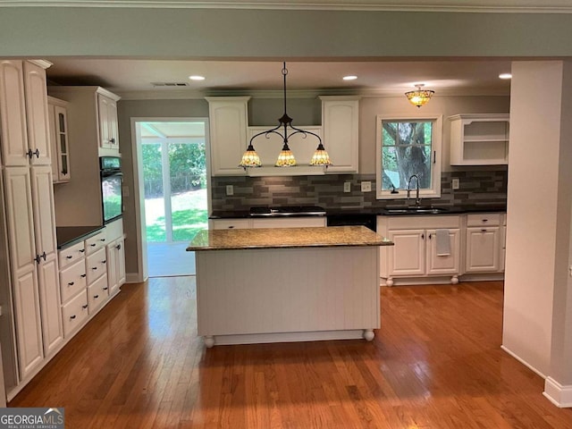 kitchen with plenty of natural light, decorative light fixtures, oven, and sink