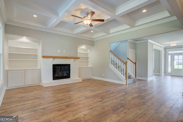 unfurnished living room featuring beam ceiling, coffered ceiling, hardwood / wood-style flooring, a fireplace, and ornamental molding