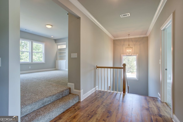 entrance foyer featuring hardwood / wood-style flooring, plenty of natural light, ornamental molding, and a notable chandelier