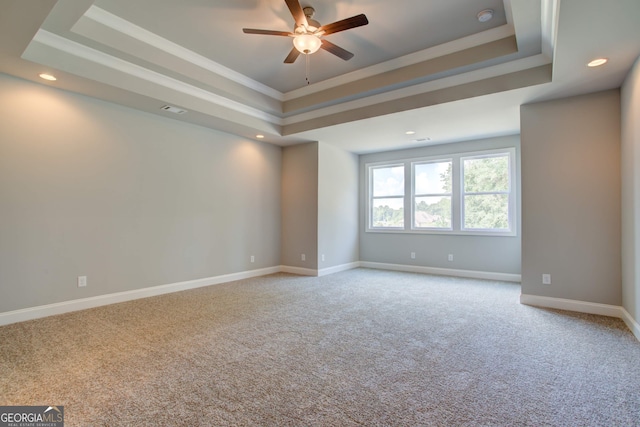 unfurnished room featuring a tray ceiling, ceiling fan, crown molding, and carpet flooring