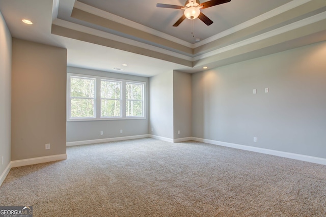 carpeted spare room featuring ceiling fan and a tray ceiling