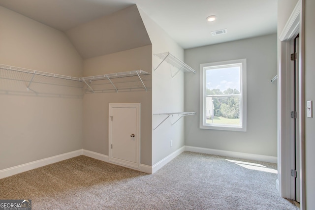 walk in closet featuring light carpet and lofted ceiling