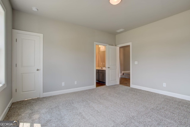 unfurnished bedroom with carpet flooring, sink, and connected bathroom