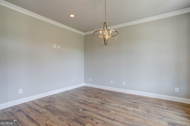 unfurnished room featuring hardwood / wood-style floors, an inviting chandelier, and ornamental molding