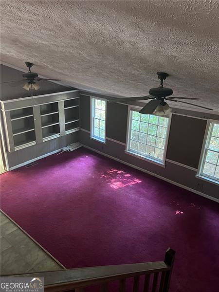 carpeted spare room featuring plenty of natural light, ceiling fan, and a textured ceiling