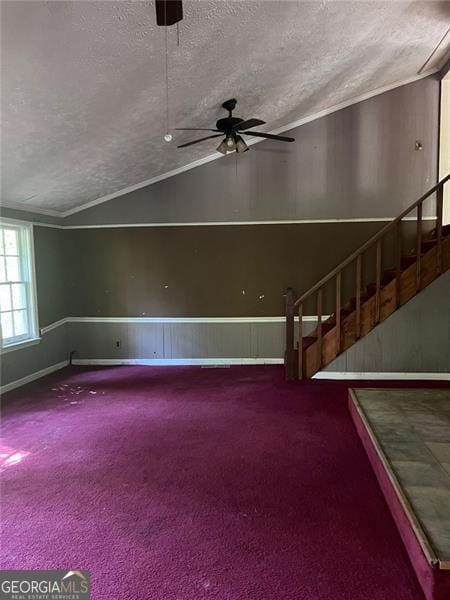 carpeted spare room featuring ceiling fan, a textured ceiling, and vaulted ceiling