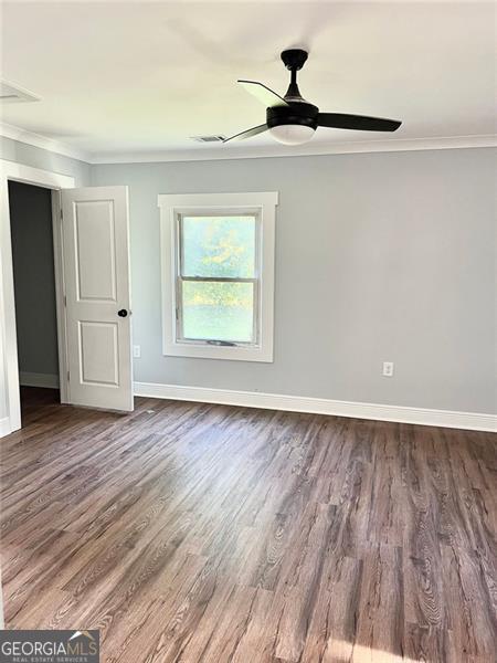 spare room with ornamental molding, dark hardwood / wood-style flooring, and ceiling fan