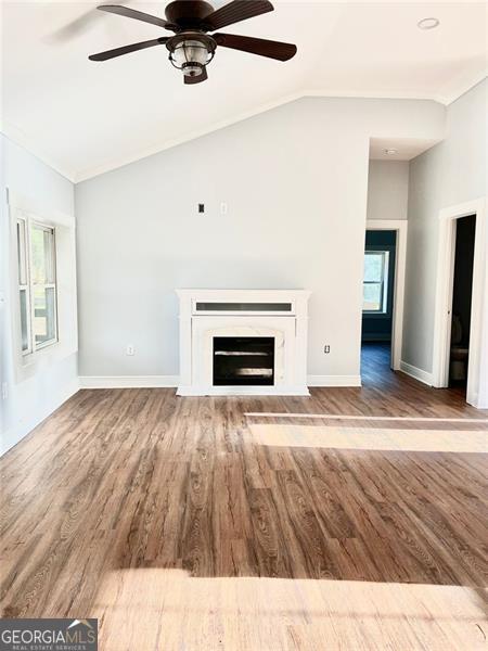 unfurnished living room featuring lofted ceiling, ceiling fan, and wood-type flooring