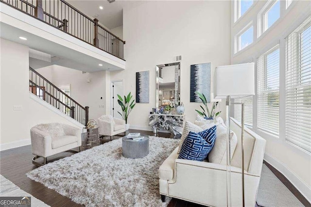 living room featuring a towering ceiling and dark hardwood / wood-style flooring