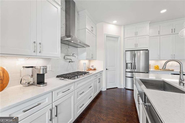 kitchen with appliances with stainless steel finishes, dark wood-type flooring, wall chimney exhaust hood, and white cabinetry