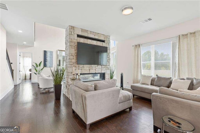 living room with a stone fireplace and dark hardwood / wood-style flooring