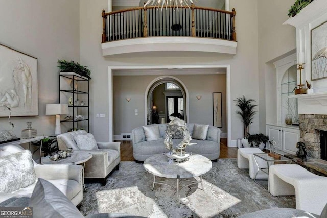 living room with wood-type flooring, a fireplace, and a towering ceiling