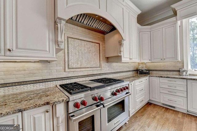 kitchen featuring light stone counters, ornamental molding, white cabinetry, range with two ovens, and light wood-type flooring