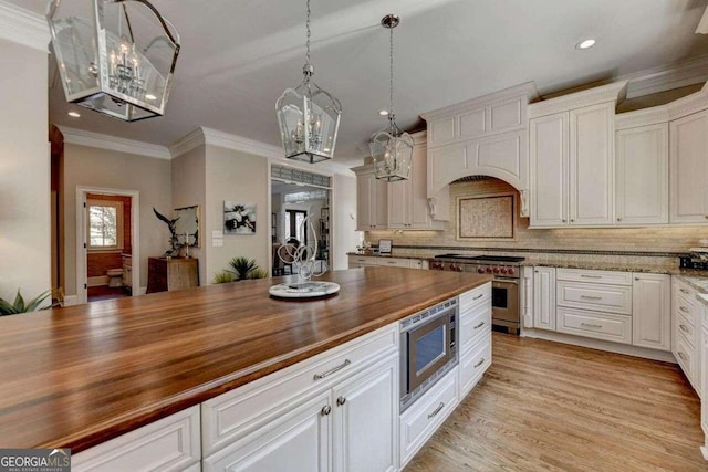 kitchen with light wood-type flooring, pendant lighting, wood counters, stainless steel appliances, and white cabinetry