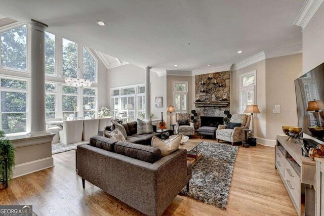 living room with light hardwood / wood-style flooring, crown molding, and decorative columns