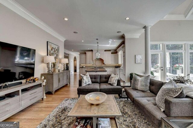 living room with light hardwood / wood-style floors, a notable chandelier, and a healthy amount of sunlight