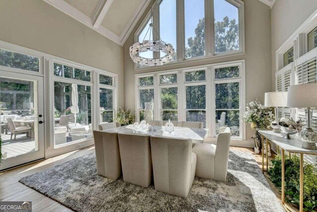 sunroom / solarium featuring vaulted ceiling with beams, plenty of natural light, and a notable chandelier