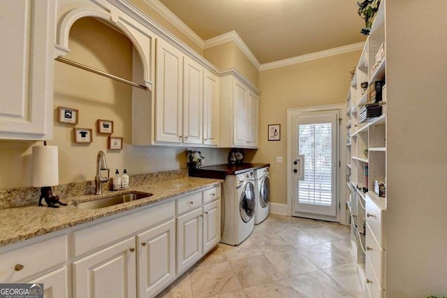 washroom with ornamental molding, washing machine and clothes dryer, sink, and cabinets