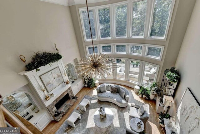 living room with hardwood / wood-style flooring, a fireplace, crown molding, and a notable chandelier