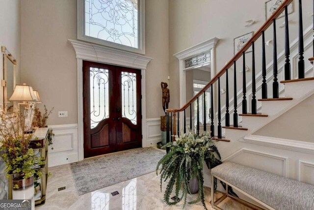 staircase with a towering ceiling, crown molding, and hardwood / wood-style floors