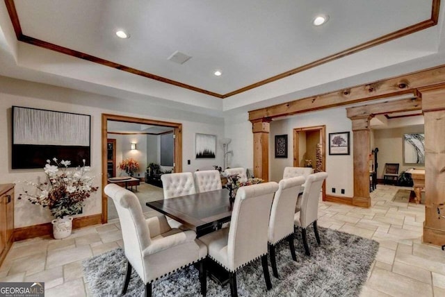 dining room with a raised ceiling, crown molding, and ornate columns