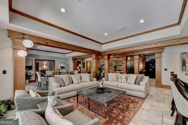 living room featuring a raised ceiling, crown molding, and ornate columns