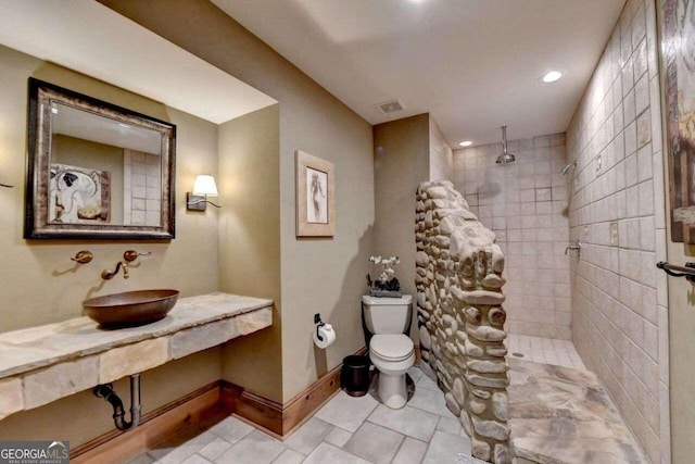 bathroom featuring vanity, tile patterned flooring, toilet, and tiled shower