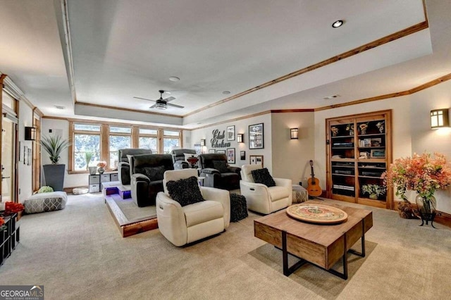 carpeted living room with ceiling fan, a tray ceiling, and ornamental molding