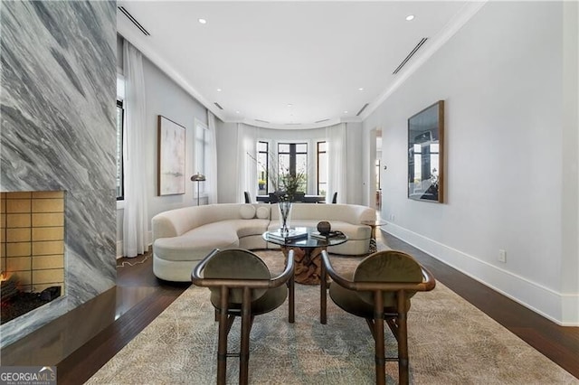 living room with a premium fireplace, crown molding, dark wood-type flooring, and tile walls