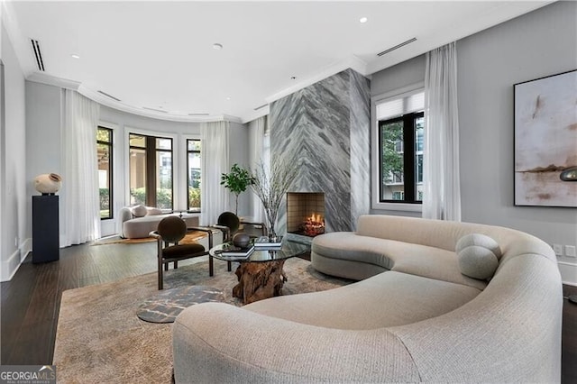 living room featuring a premium fireplace, crown molding, plenty of natural light, and dark hardwood / wood-style floors