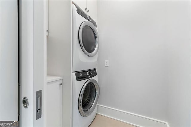 laundry area featuring stacked washer and clothes dryer and cabinets