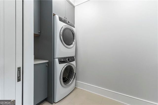 clothes washing area featuring stacked washer / dryer and cabinets