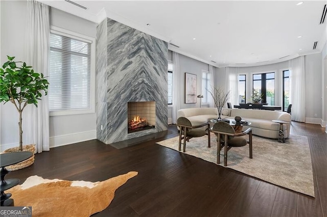 living area with ornamental molding, a premium fireplace, and dark hardwood / wood-style flooring