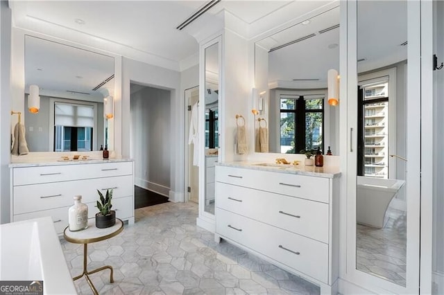 bathroom with ornamental molding, a tub to relax in, and vanity